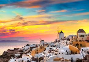 A white buildings with windmills and a sunset

Description automatically generated